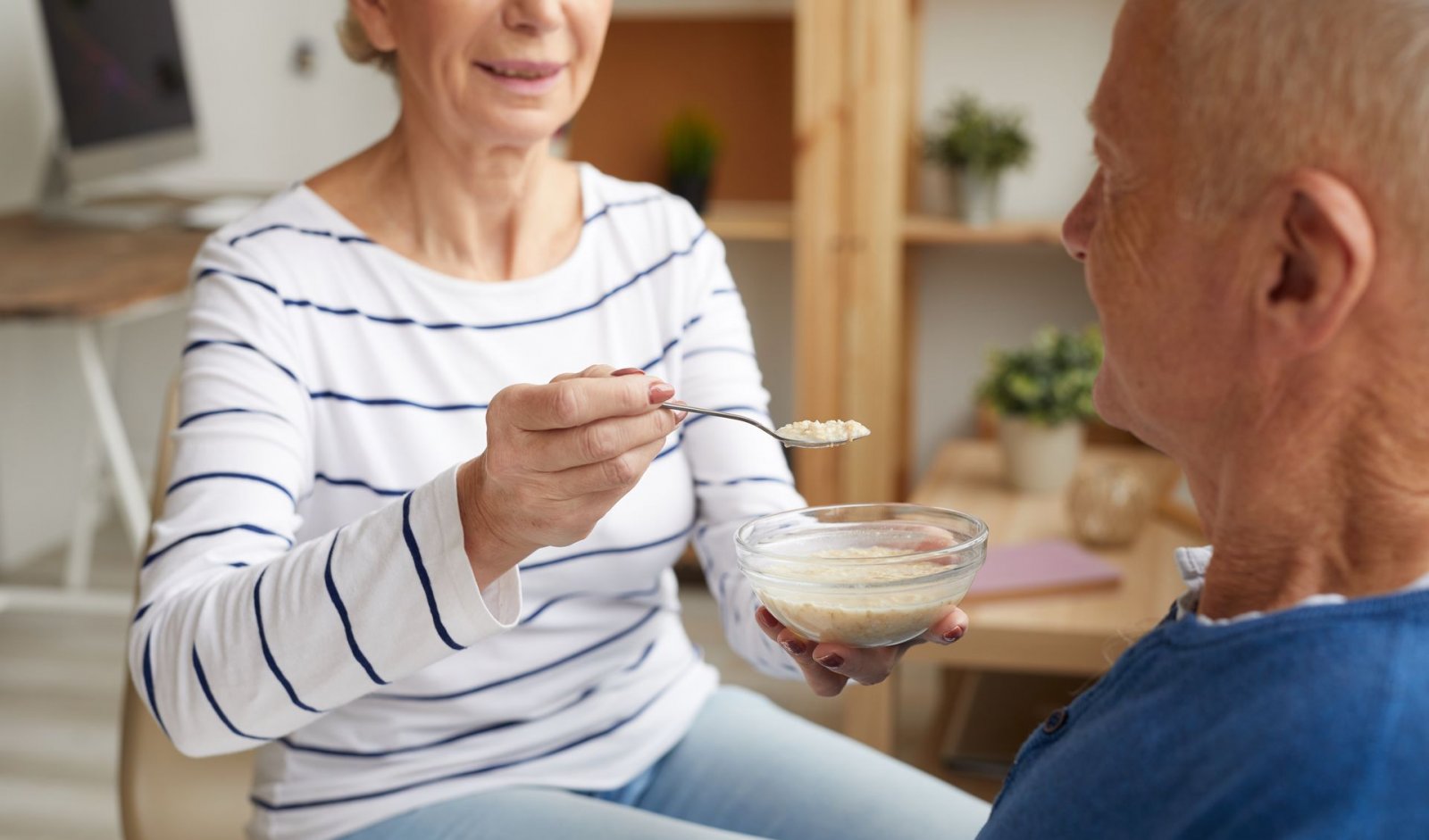 Senior man being fed oatmeal by his wife