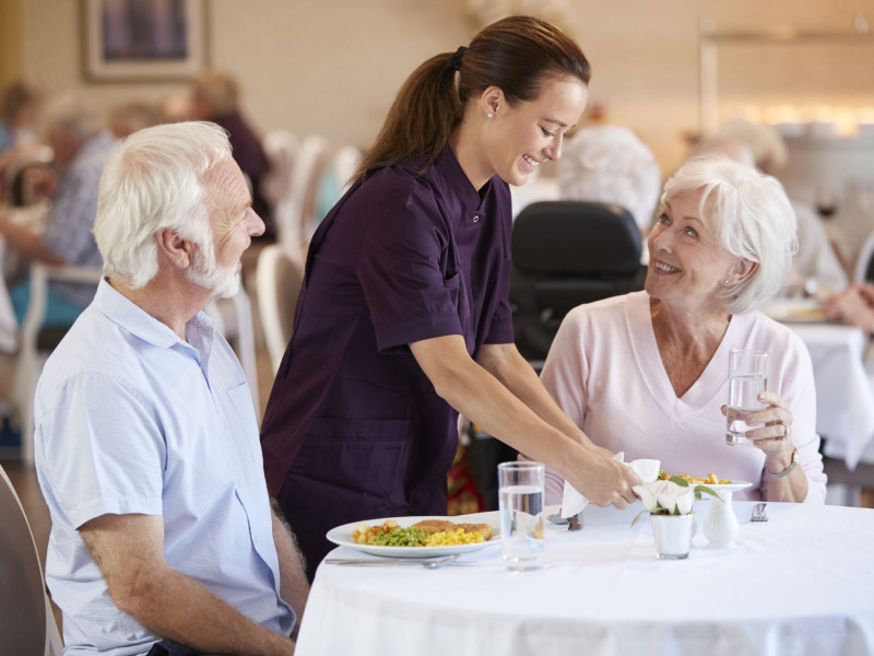 A waitress serves breakfast to two seniors at a nice restaurant