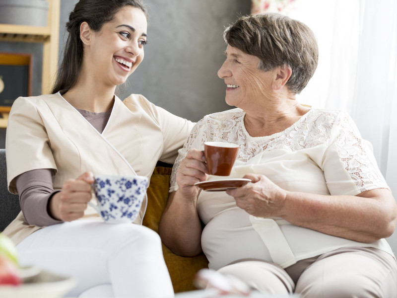 A senior and her nurse share a cup of tea
