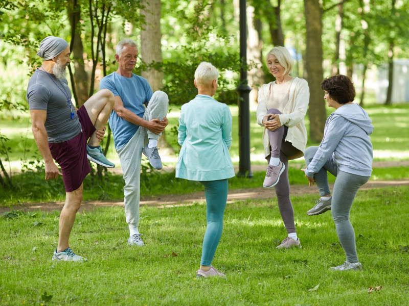 A group of seniors stretch in a park