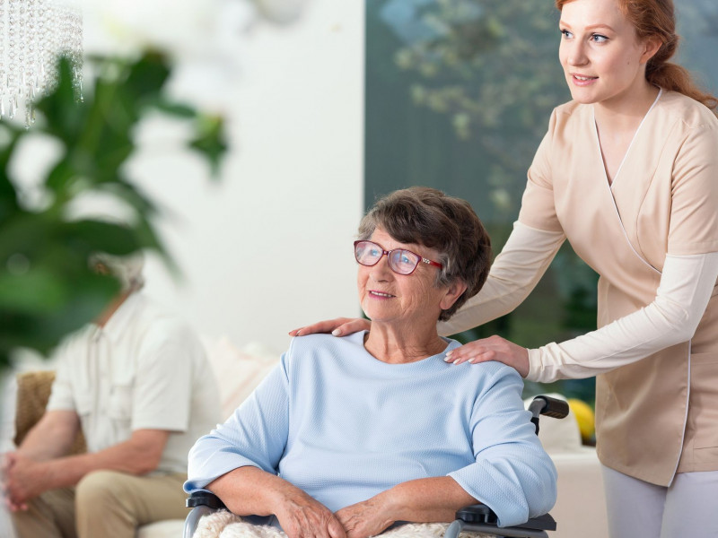 A senior woman in a wheelchair and a nurse talking