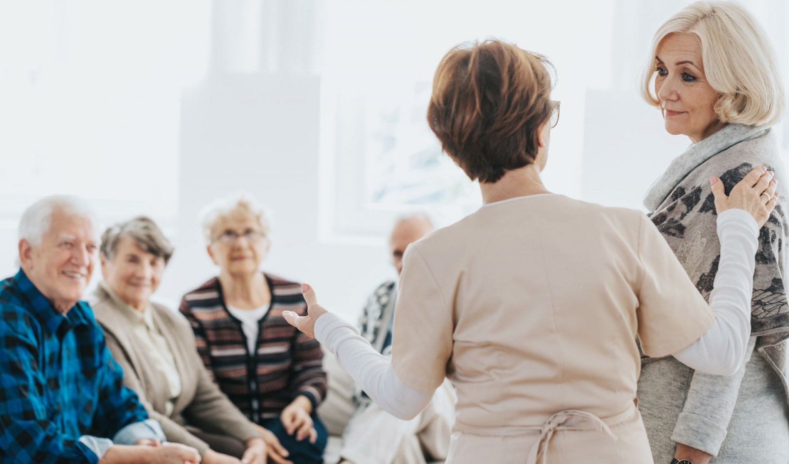 A nurse introduce a senior woman to a group of other seniors in assisted living