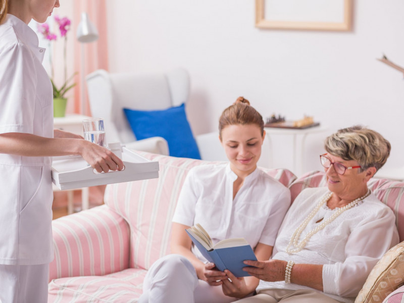 A staff member reads a book with a senior woman