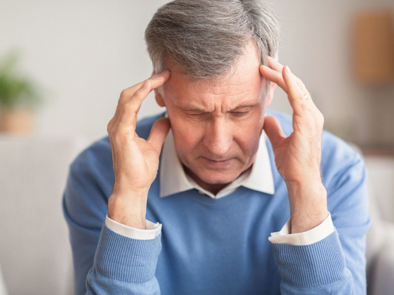 A senior man touching his temples as if he has a headache