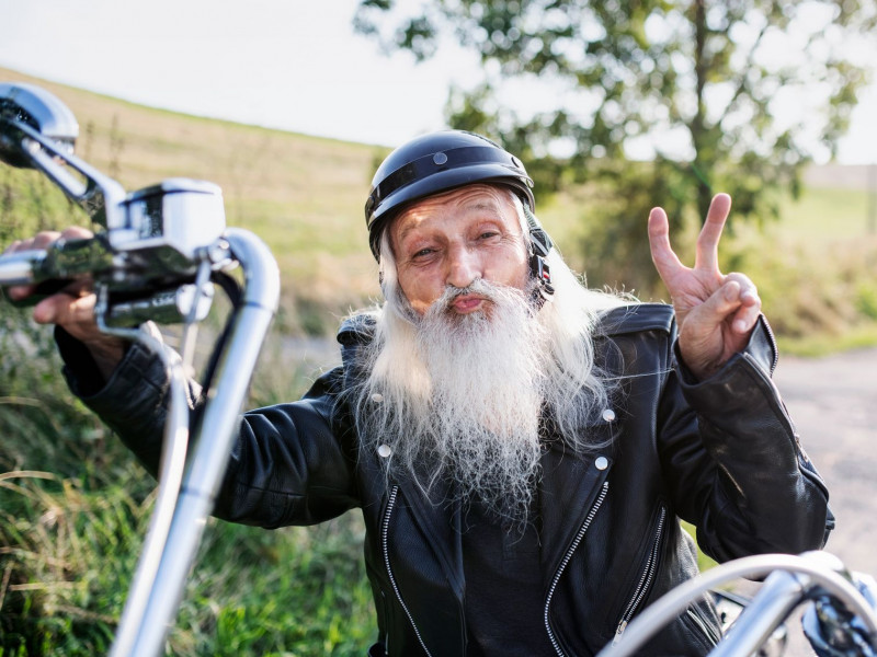 A senior on a motorcycle flashes a peace sign at the camera