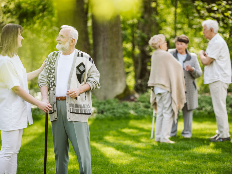 A group of seniors socialize outdoors in a garden