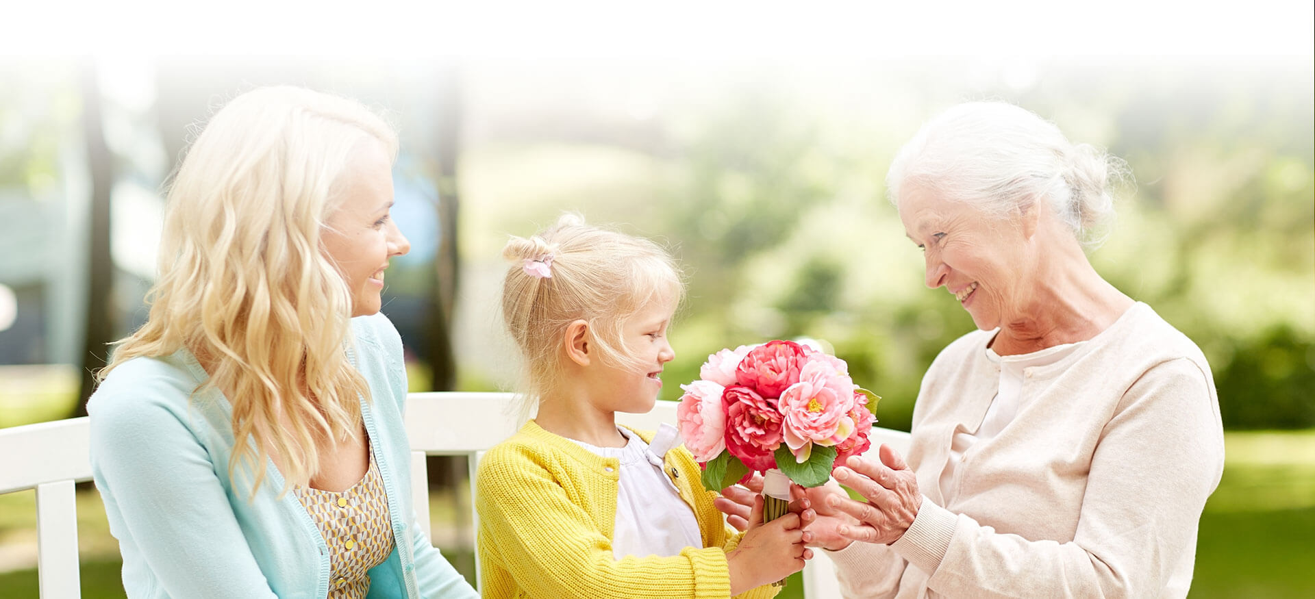 Elderly woman receiving flowers from her great grand daughter
