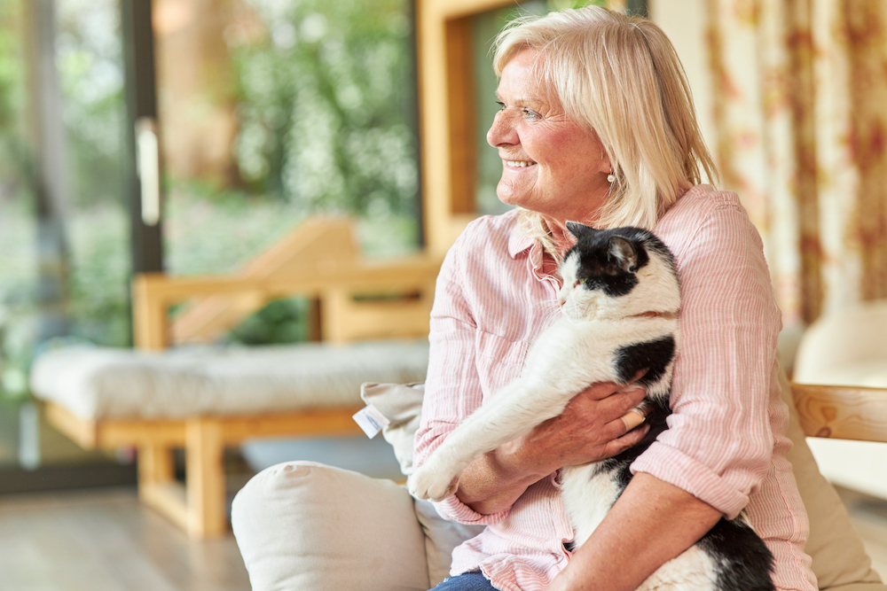 A senior woman holds her black and white cat