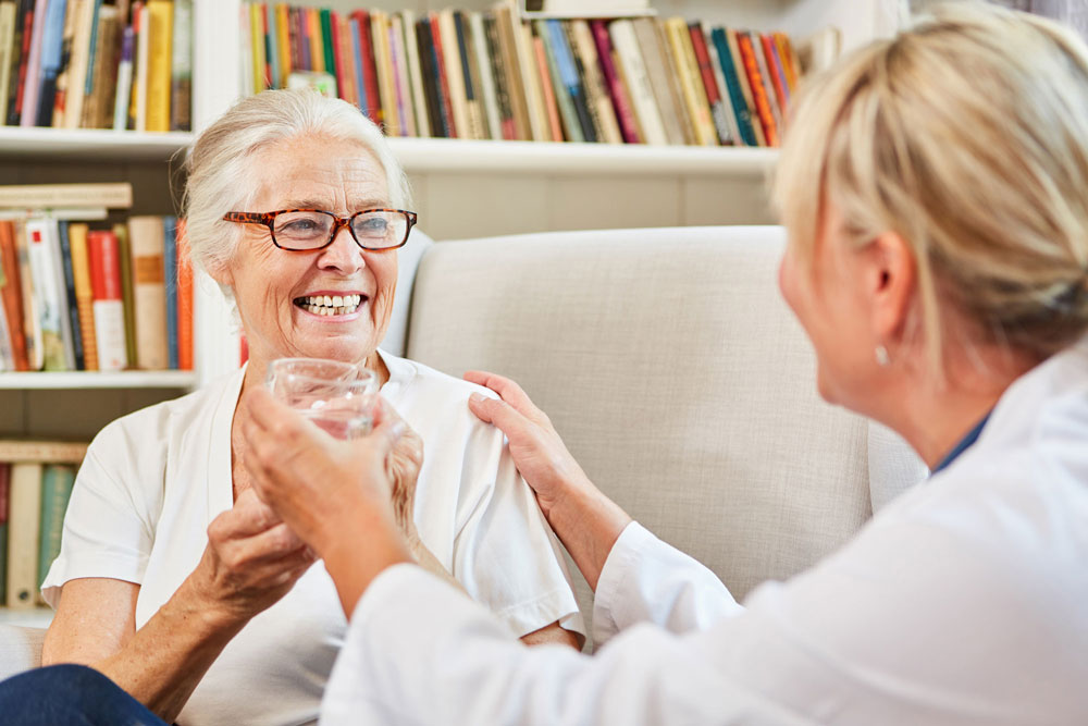 Senior woman accepts a glass of water from a woman