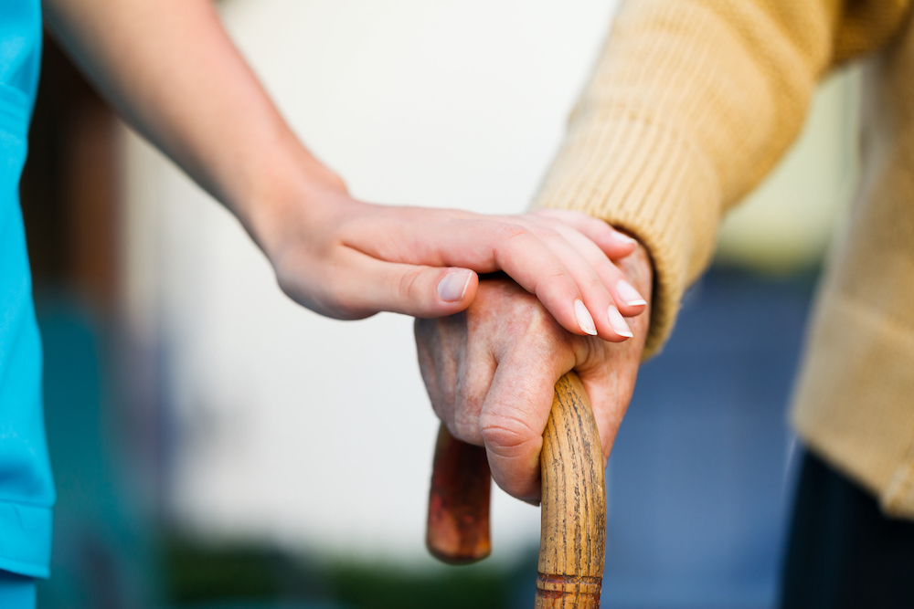 A caregiver holds a senior's hand