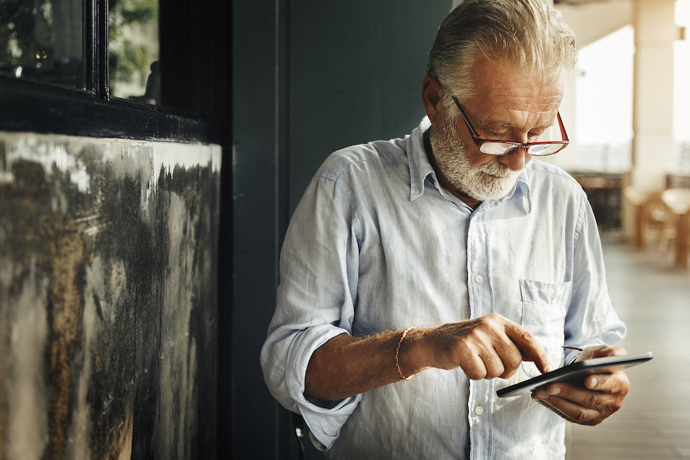 A senior man scrolls through social media on his phone