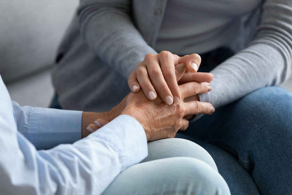 A caregiver holds hands with a senior woman