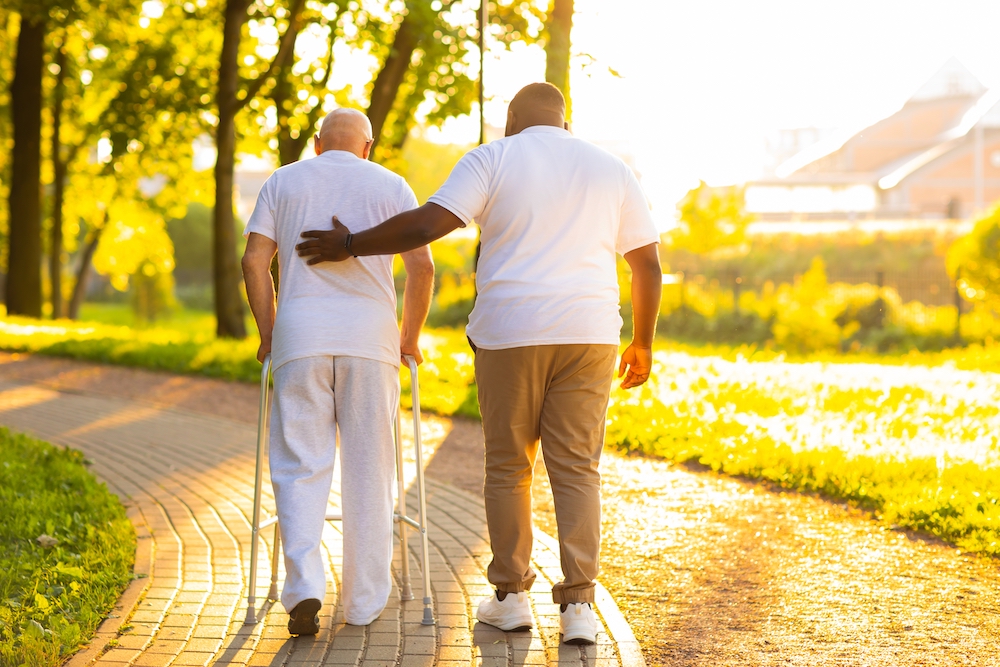 A senior man and respite caregiver out on a walk in the park