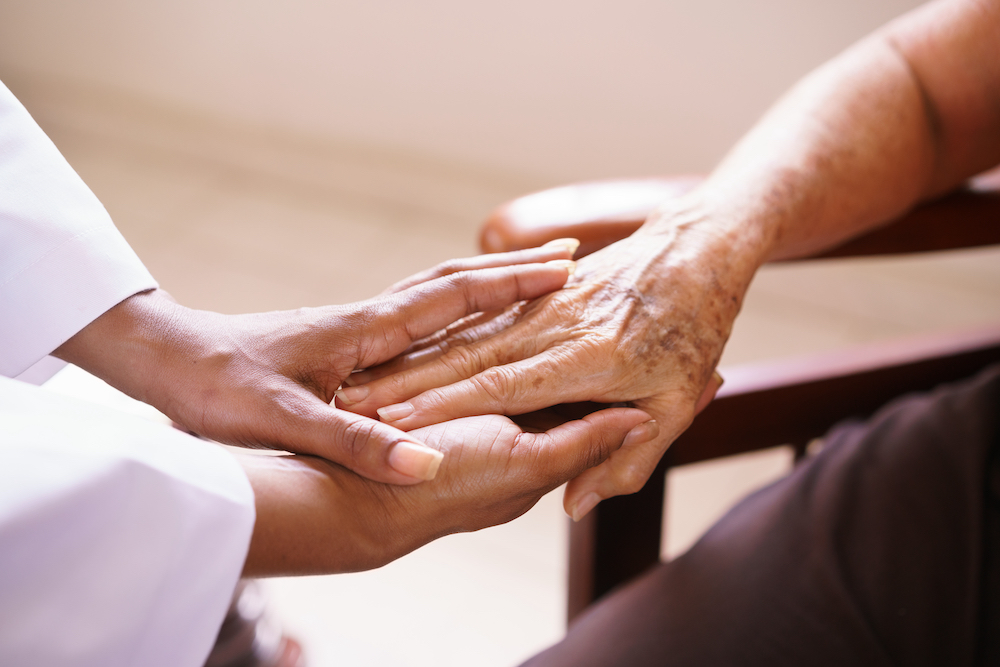 A senior woman holds hands with her respite caregiver