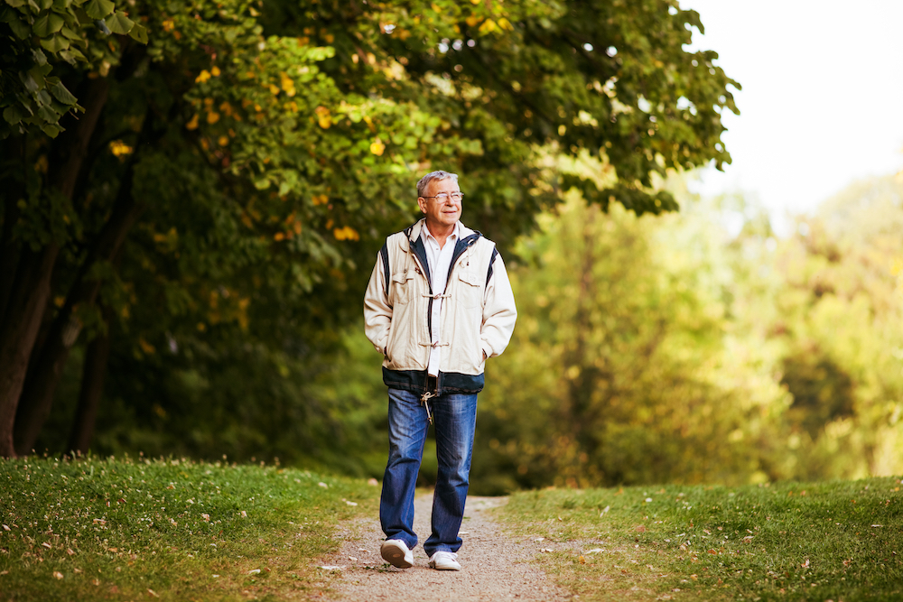 A senior man takes a walk through a park
