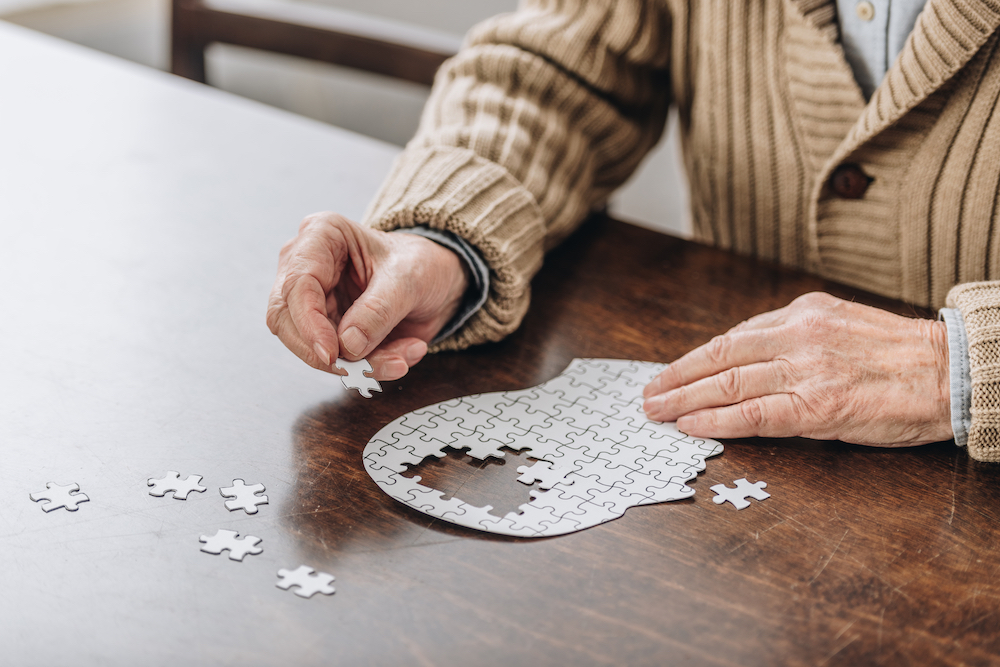 A senior man completes a brain shaped puzzle