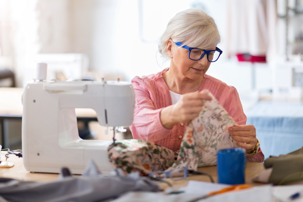 A senior woman works at her sewing machine