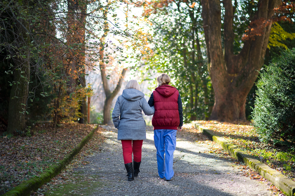 A senior and caregiver go on a fall walk together