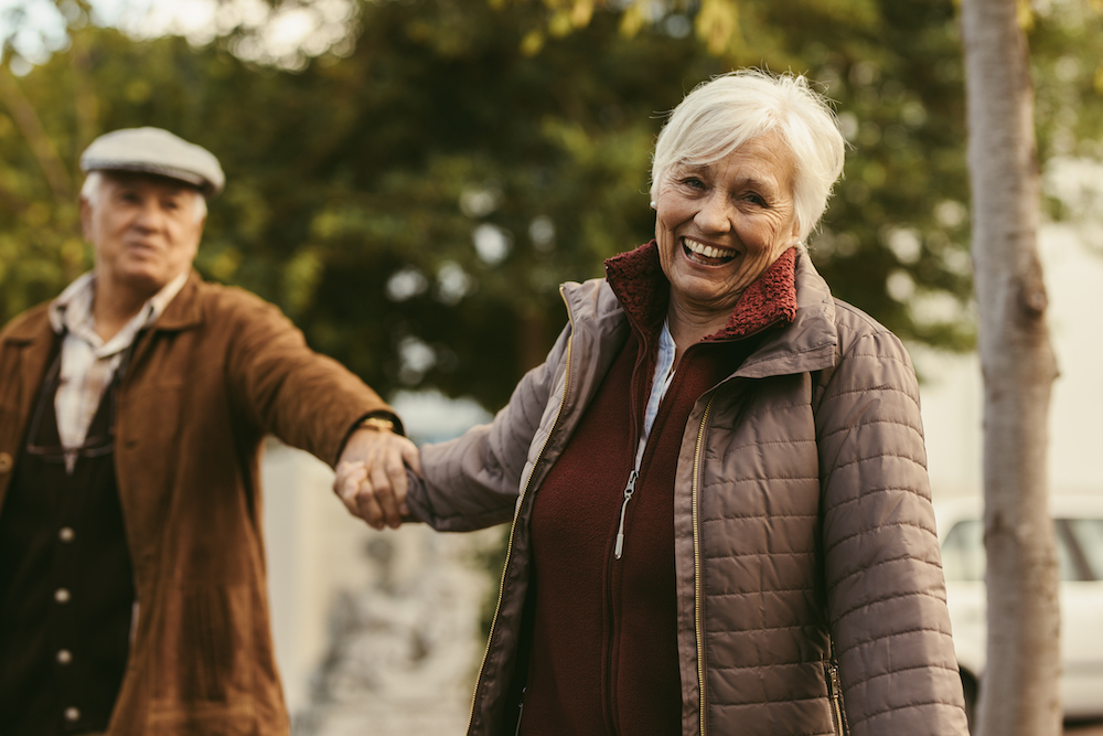 A senior couple hold hands as they walk outside