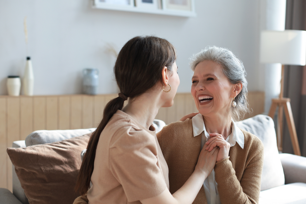 A senior woman and her daughter talk and hold hands