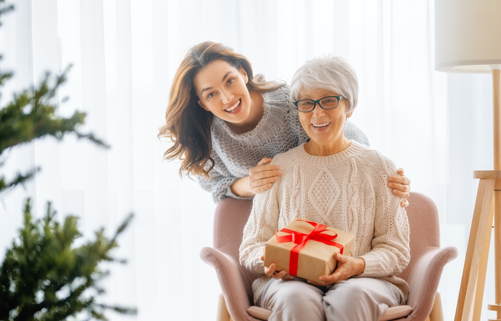 A senior woman and her daughter hold a holiday gift