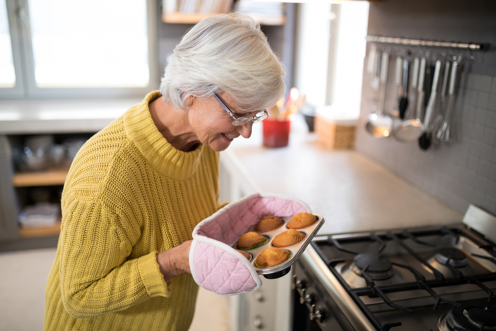 A senior woman baking muffins fresh from the oven 