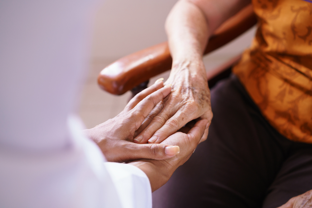 A senior holding hands with her caregiver at the affordable memory care in Oceanside