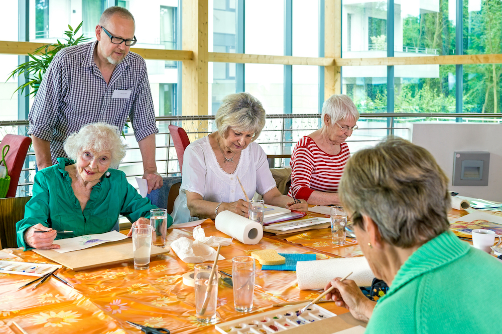 An art instructor at Oceanside memory care services leading senior residents in an art class