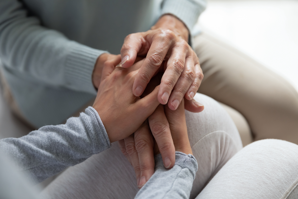 A senior woman and a caregiver hold hands at the short term respite care in Oceanside