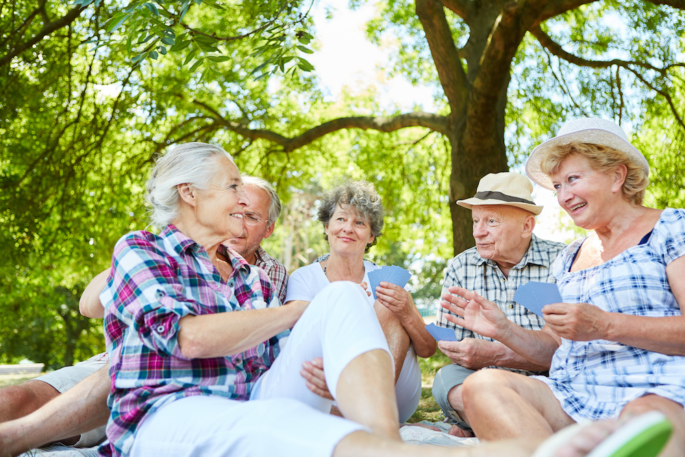 A group of senior friends play a card game together outside