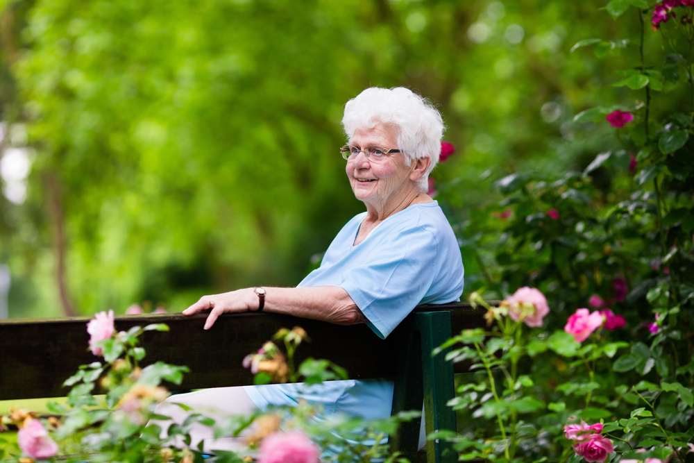 Senior woman outside on bench enjoying memory care services oceanside