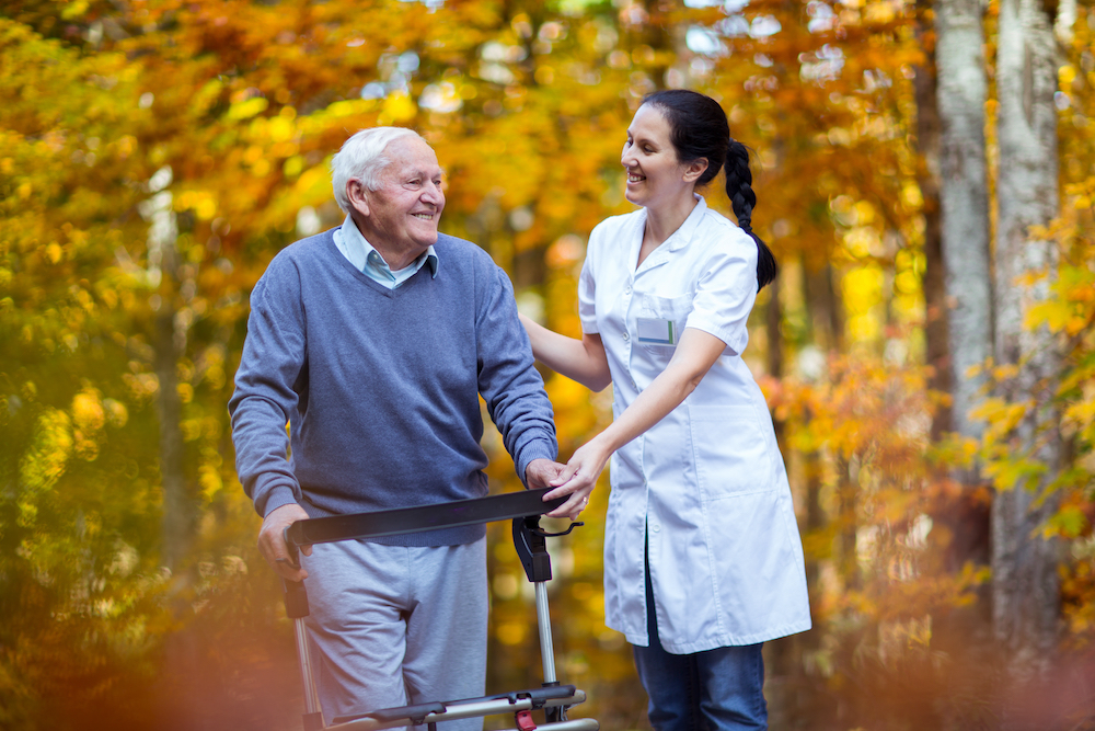 A nurse and a senior resident go for a walk outdoors
